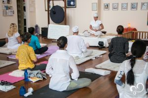 Praticantes de Kundalini yoga sentados para prática em salão de yoga durante Retiro espiritual